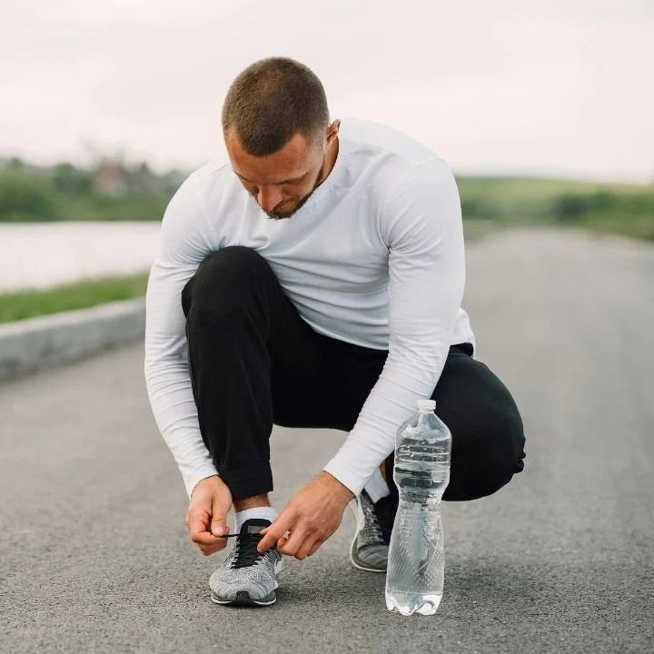 Man tying new running shoes on road before workout.