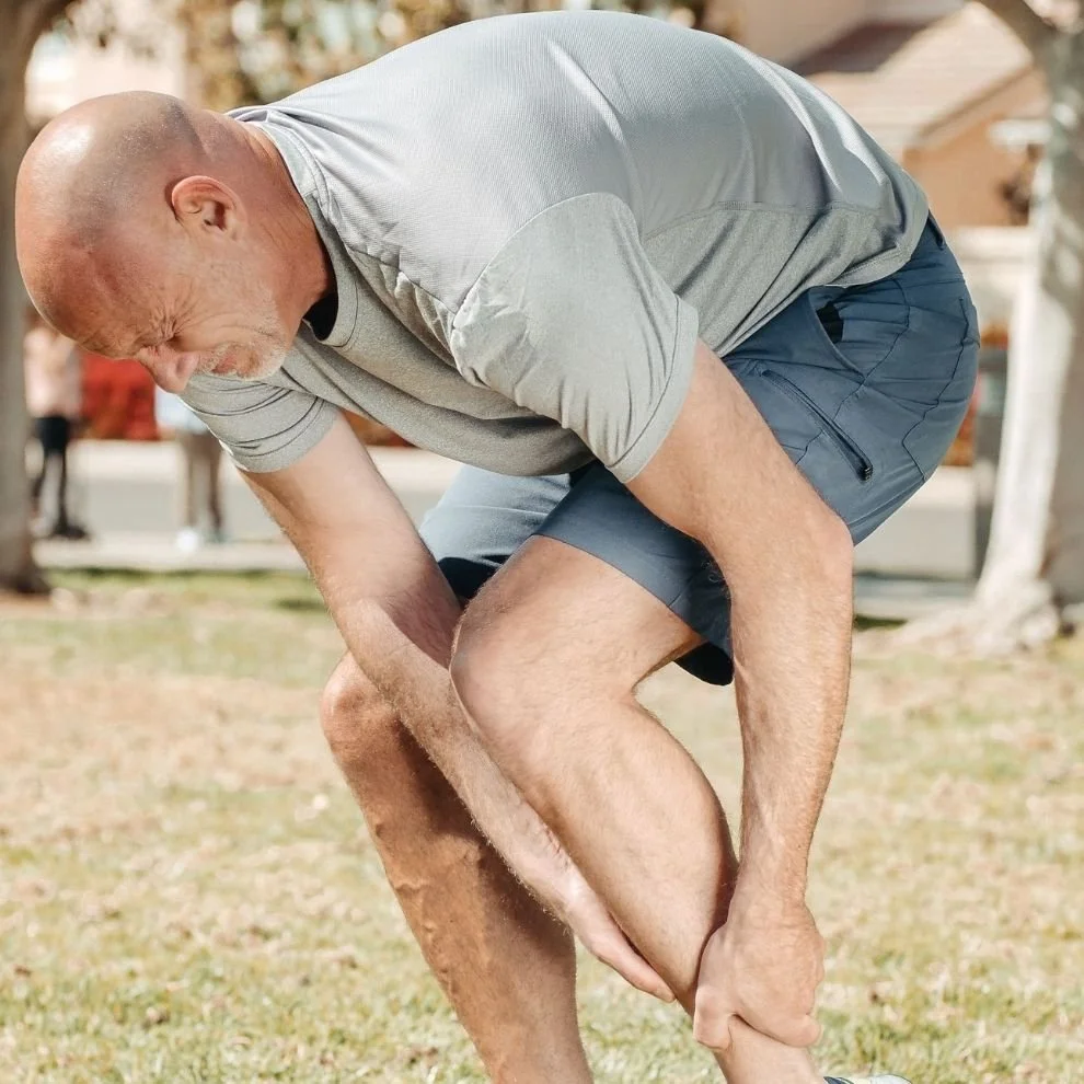 Runner holding painful shin after exercise due to persistent shin splint symptoms.