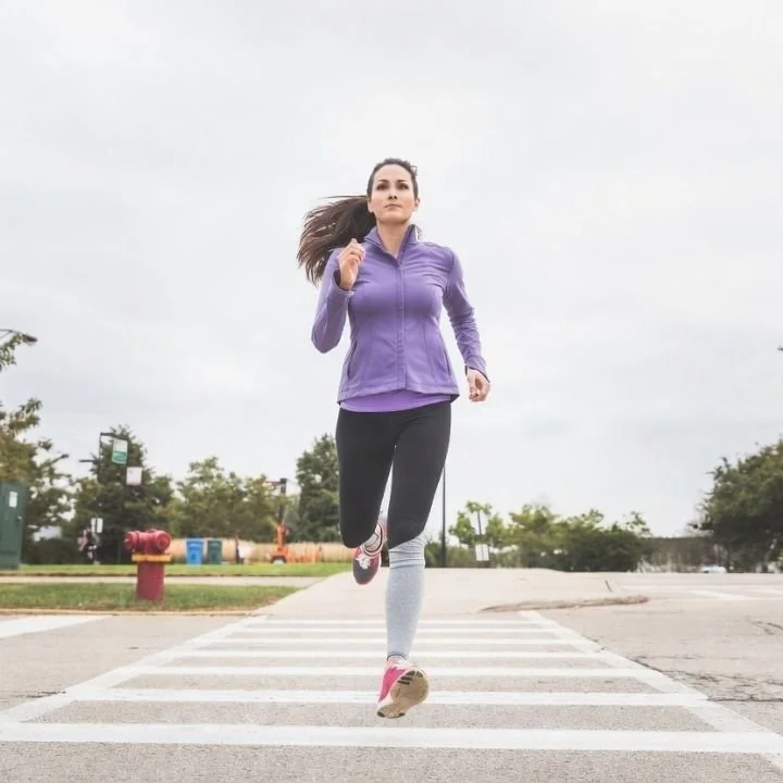Woman running across crosswalk during outdoor training session.
