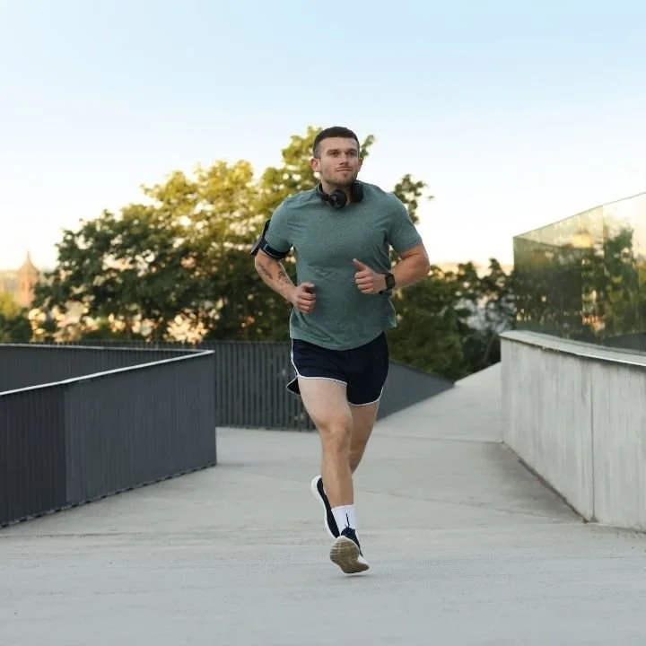 Man jogging on elevated urban walkway during evening workout.
