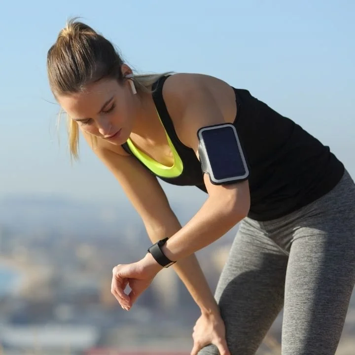Woman pausing during run to check smartwatch and heart rate.