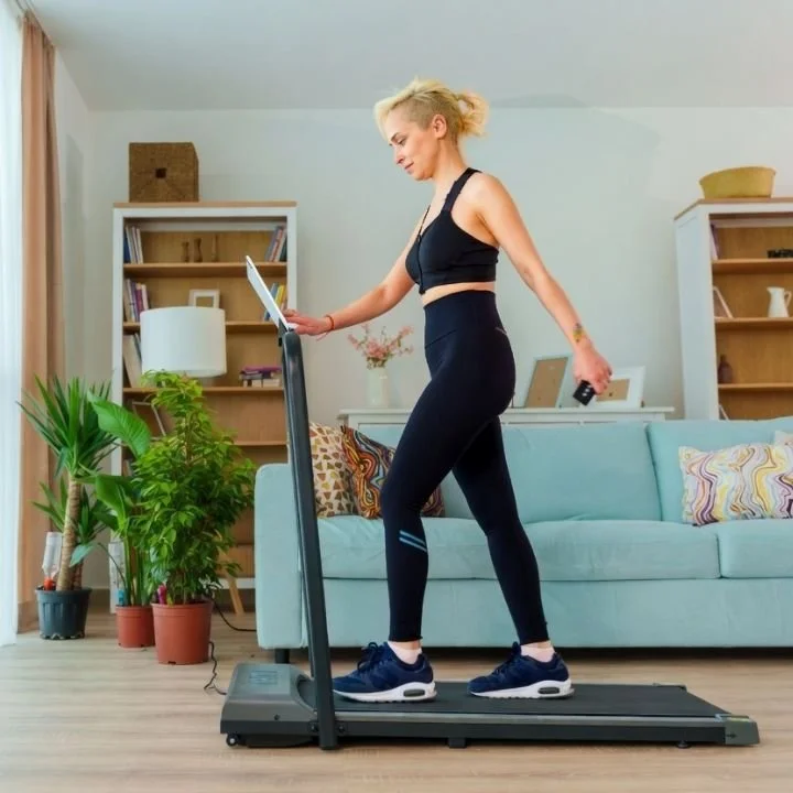 Woman walking on treadmill at home for low-impact training.