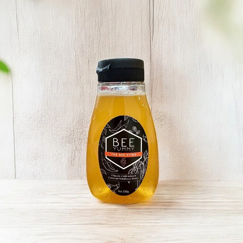 Bee Yummy Bee Sting Hot Honey squeezable bottle on a light wooden background.