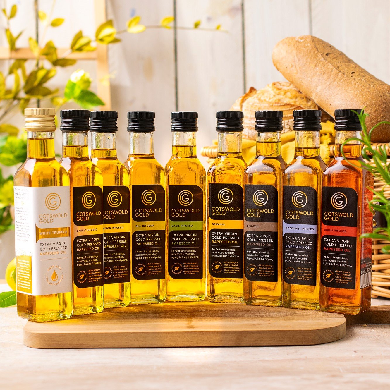 Selection of Cotswold Gold cold-pressed rapeseed oils and infused oils displayed on a wooden board.