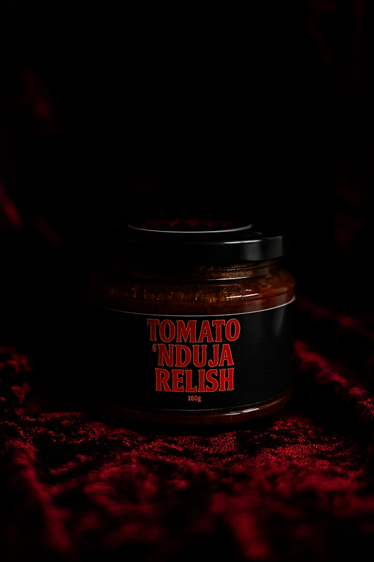 Tomato and 'nduja relish jar on dark red fabric.