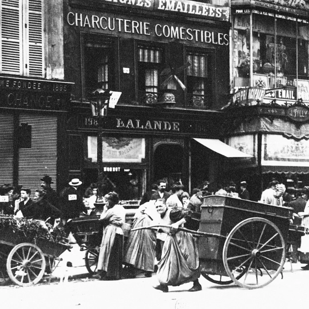 Historic black and white photograph of a French charcuterie shop with people transporting cured meats by cart.
