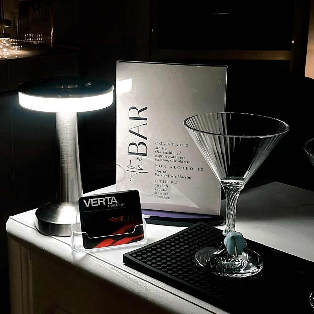 Bespoke cocktail menu positioned on mobile bar with verta events business cards, lamp and cocktail glass