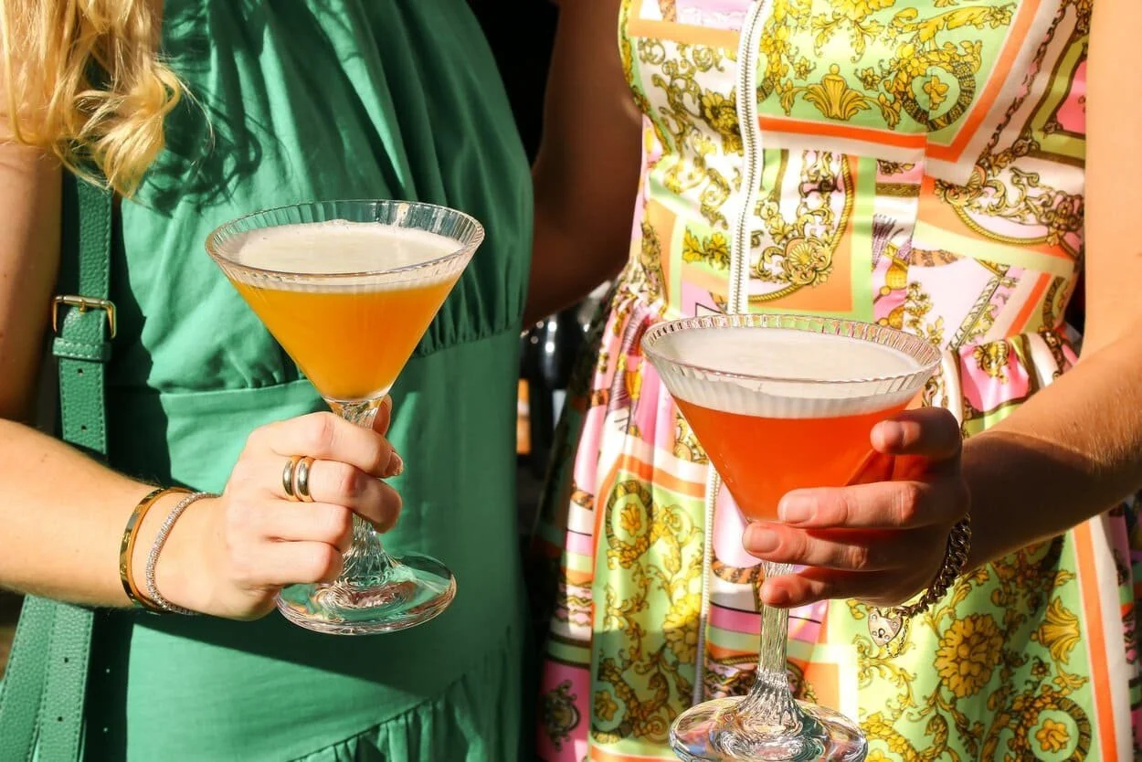 Females in colourful dresses holding colourful cocktails