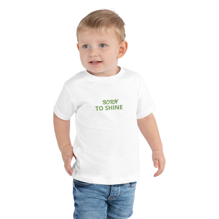 Young child wearing a custom designed white T-shirt with the slogan 'Born to Shine' in green lettering.