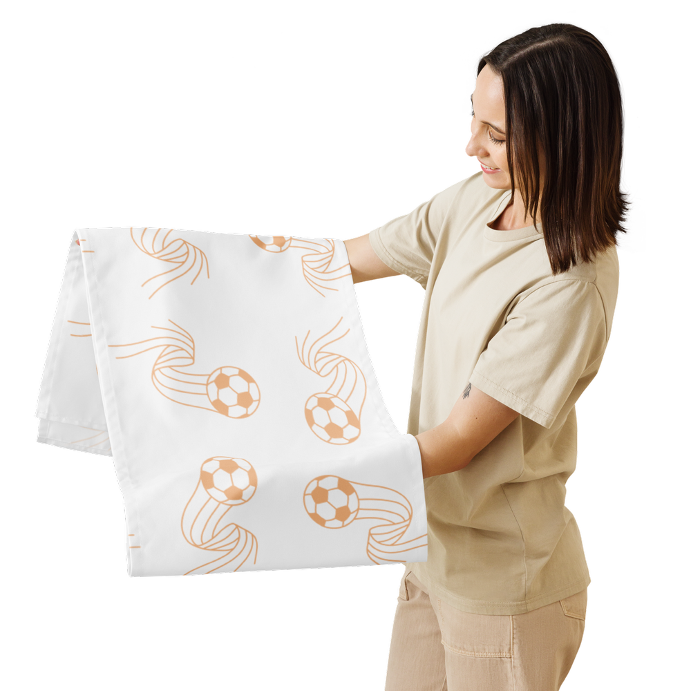 A woman is hanging a white piece of fabric with a soccer ball pattern on it from a wall-mounted towel rack.
