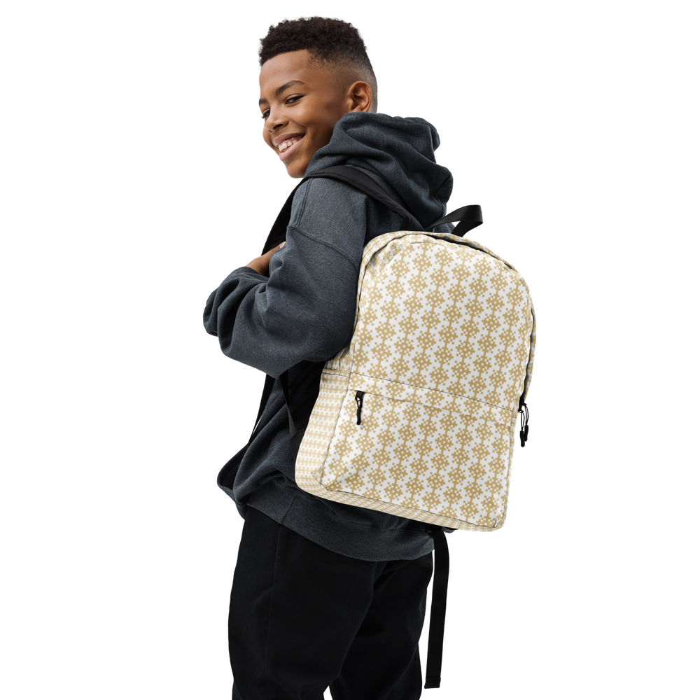 A smiling young boy with a short haircut wearing a dark hoodie and pants, carrying a beige backpack with a white and brown floral pattern.