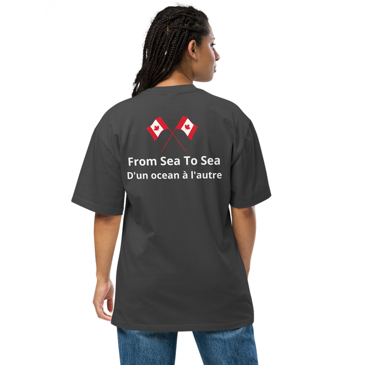 Back view of young lady wearing oversized faded black t-shirt with 2 Canadian flags and  "From Sea To Sea" printed in white and with French translation below "D'un ocean a l'autre". A patriotic statement in display of the National Motto of Canada