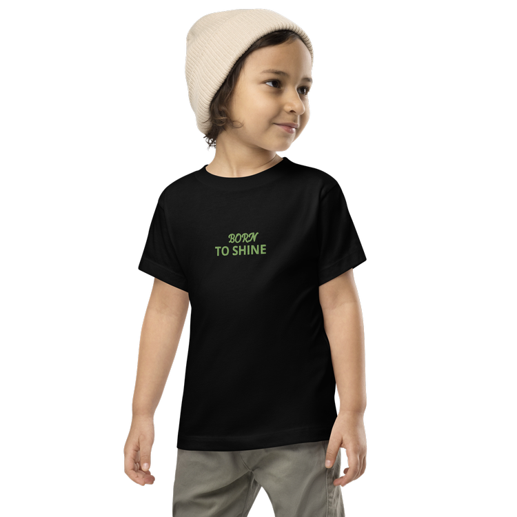 Child wearing black T-shirt with 'Born to Shine' text and beige beanie. Children's casual wear.