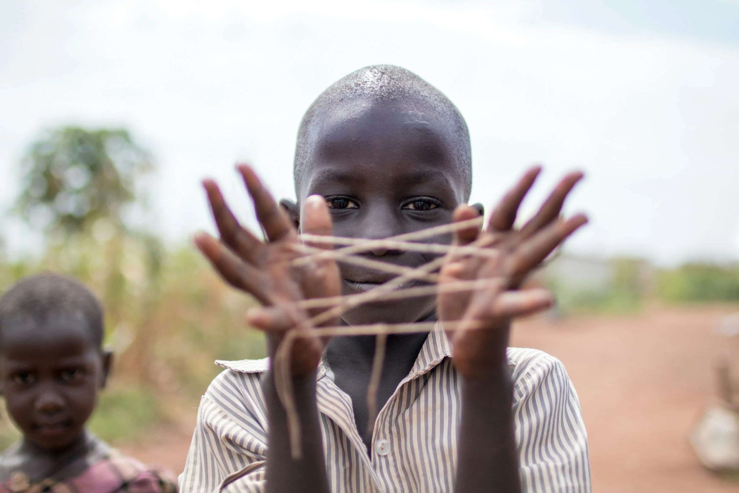 Child outdoors playing with string, representing who you can impact with participating in workplace engagement