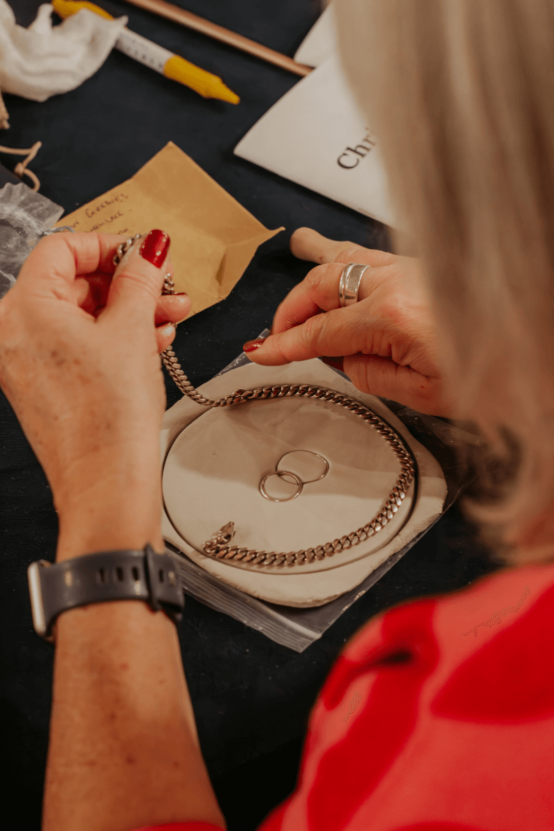 A widow creating a memorial keepsake using her husband’s bracelet and their wedding rings during a meaningful retreat activity