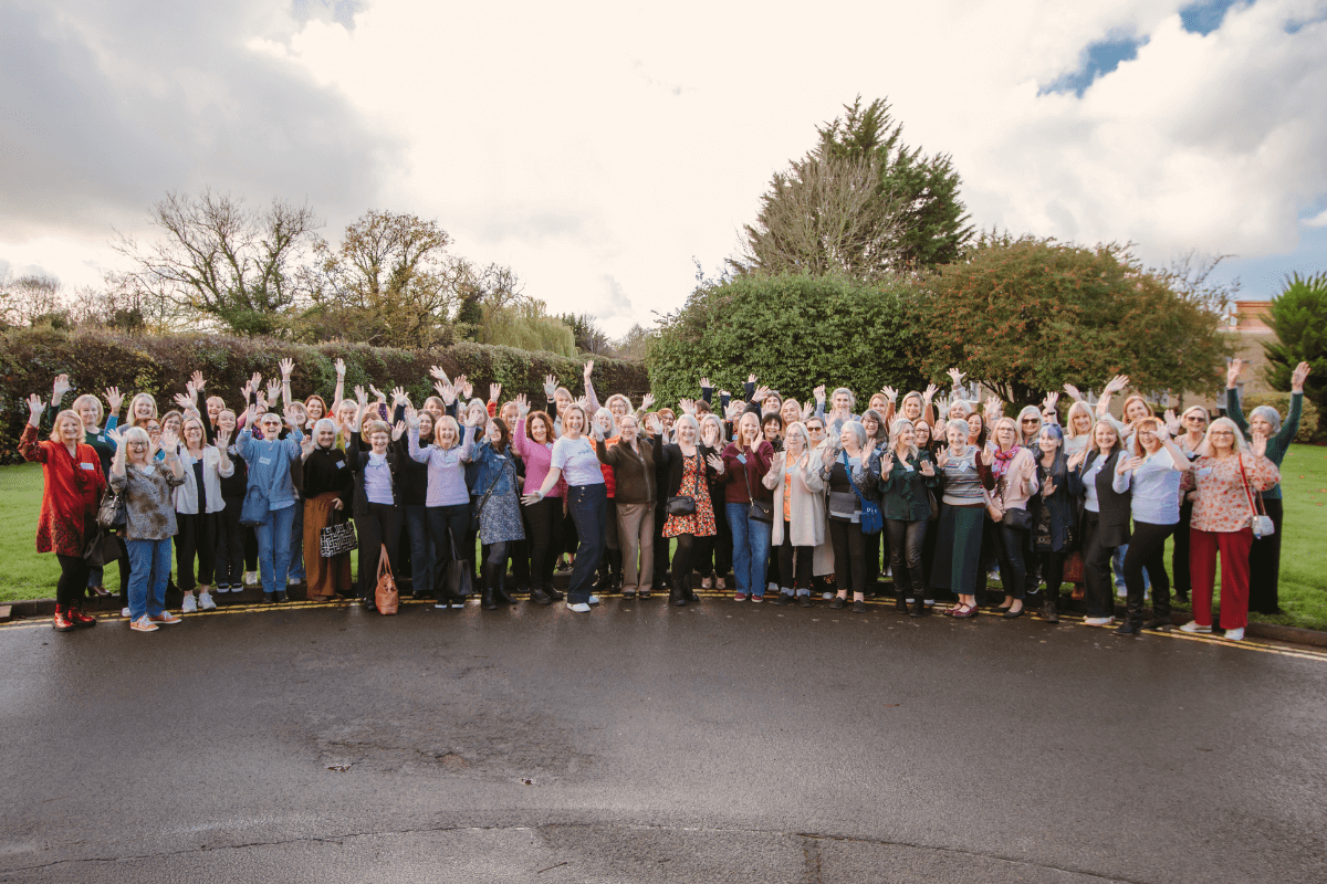 Widows standing together with hands raised, sharing a powerful moment of unity, hope, and healing at the retreat