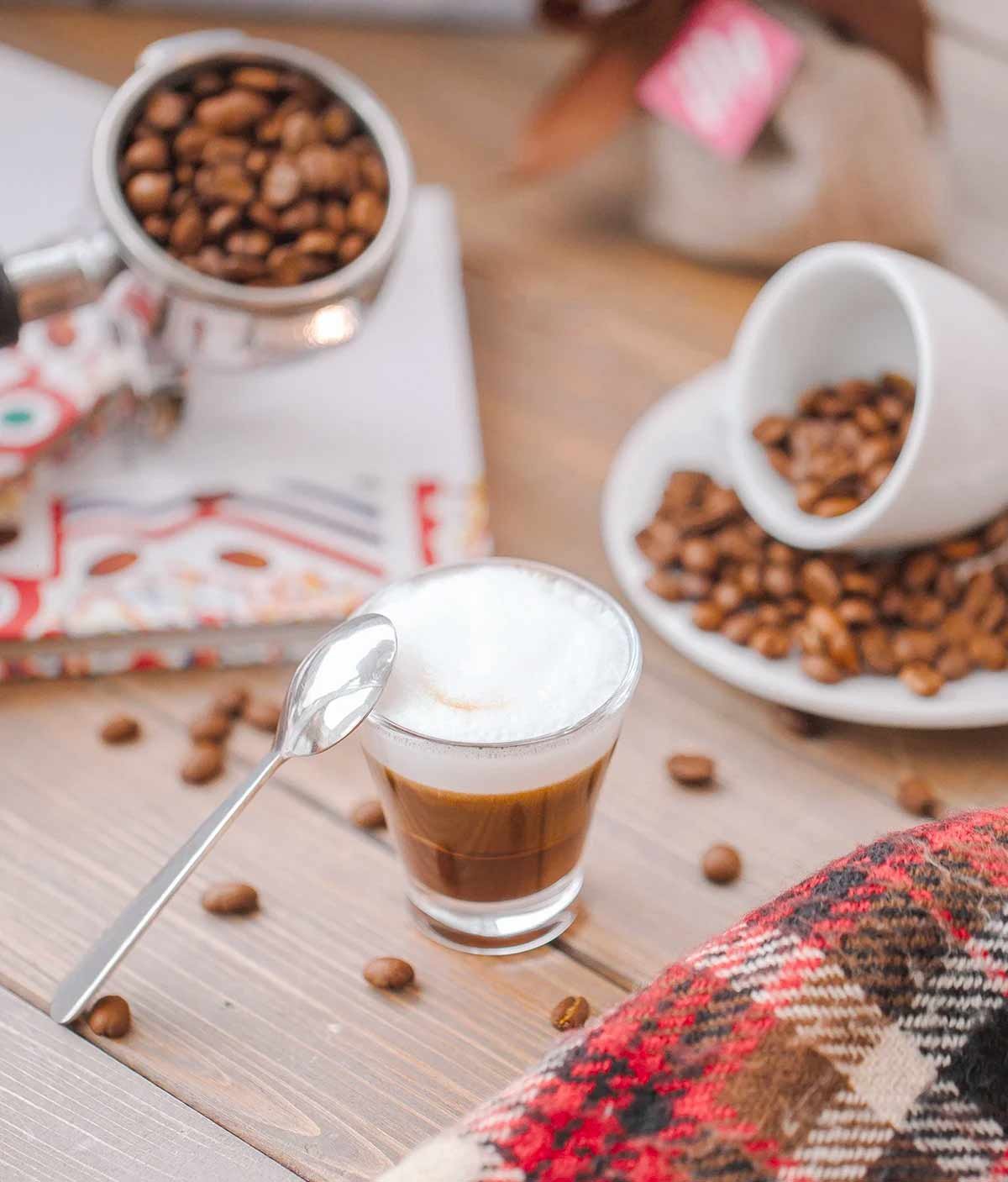 Latte Macchiato im Glas mit Kaffeebohnen auf Holztisch