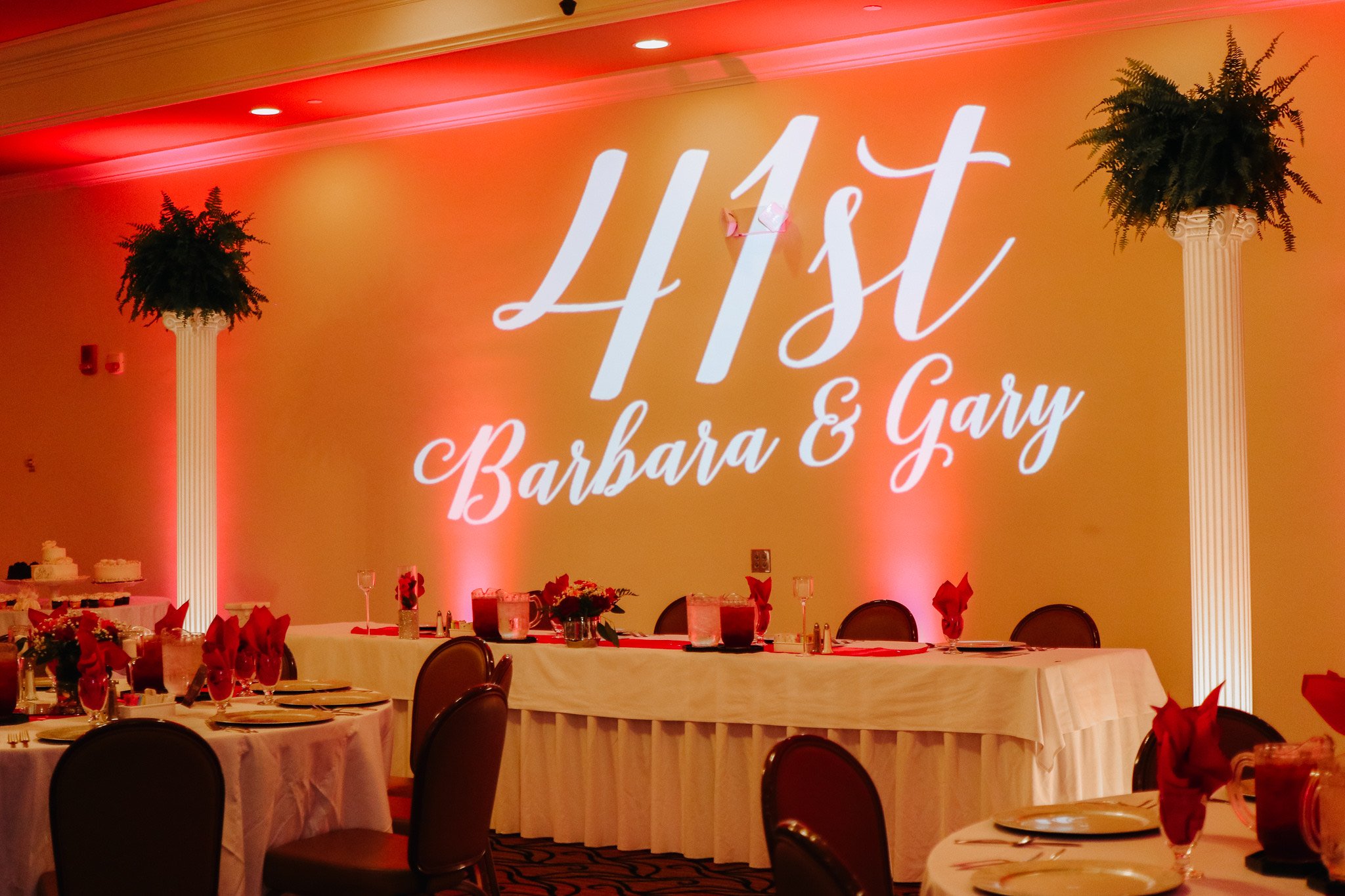 Anniversary party setup with "41st Barbara & Gary" monogram projected on the wall.