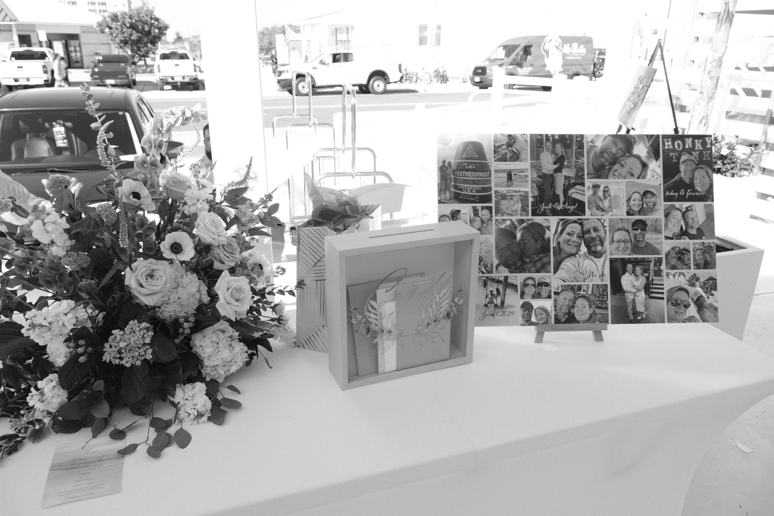 Wedding gift table with floral arrangement, photo collage, and gift box on a white tablecloth.