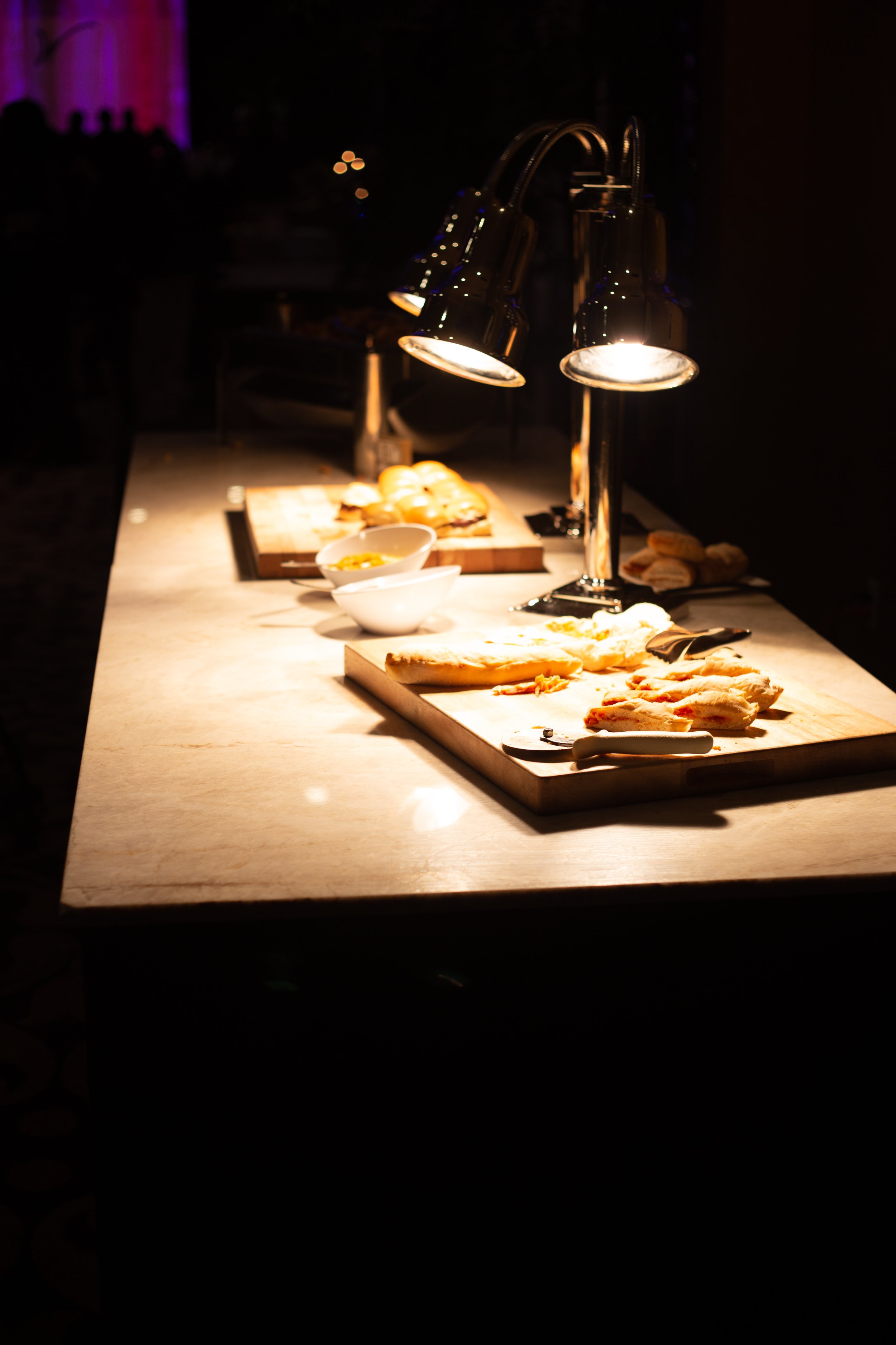Buffet table with heat lamps, wooden boards, bread, and bowls