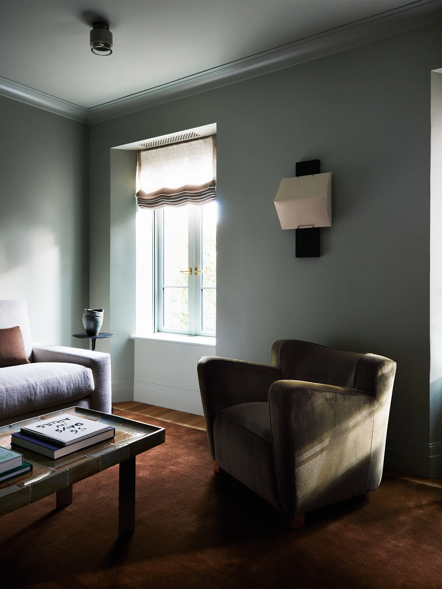 View of den with side chair, sofa, coffee table.