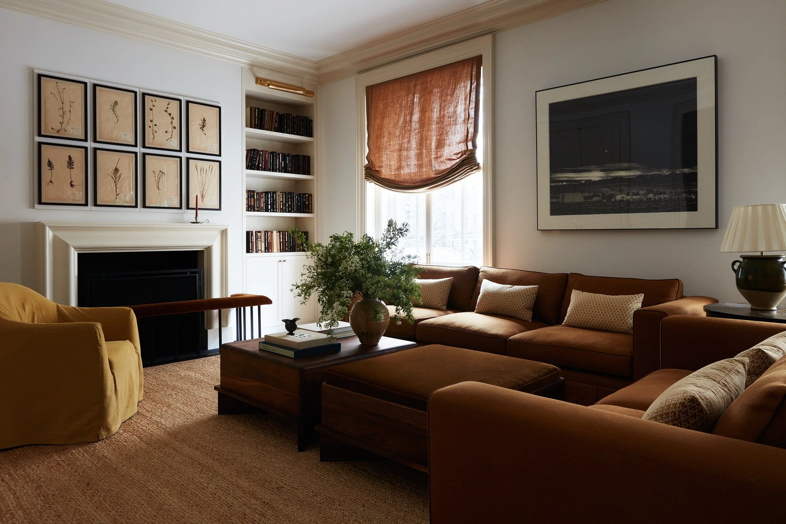 Living room view of two sofas, side chair, coffee tables, vase, books, fireplace, art.
