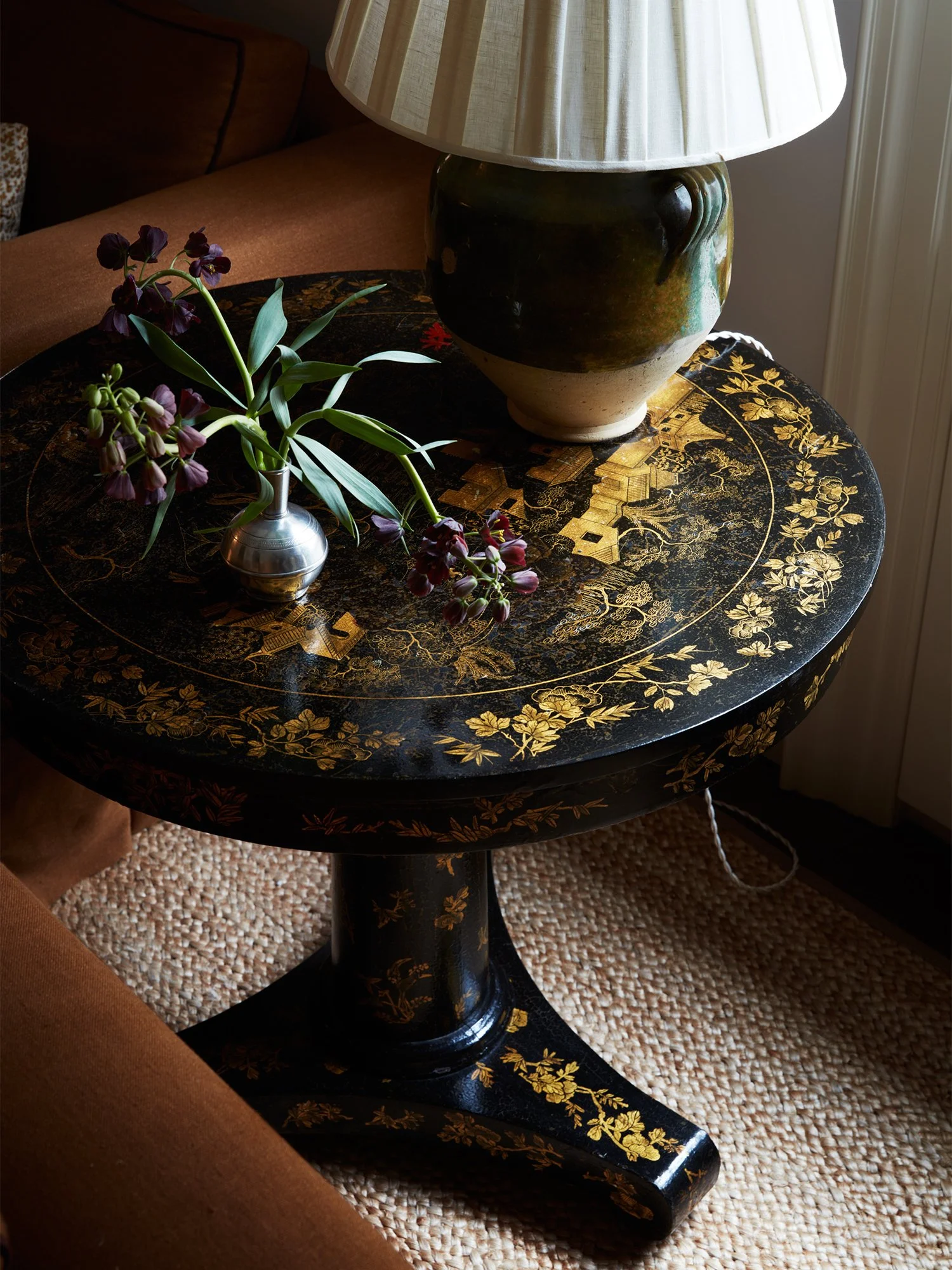 Closeup of side table with table lamp and flower vase.