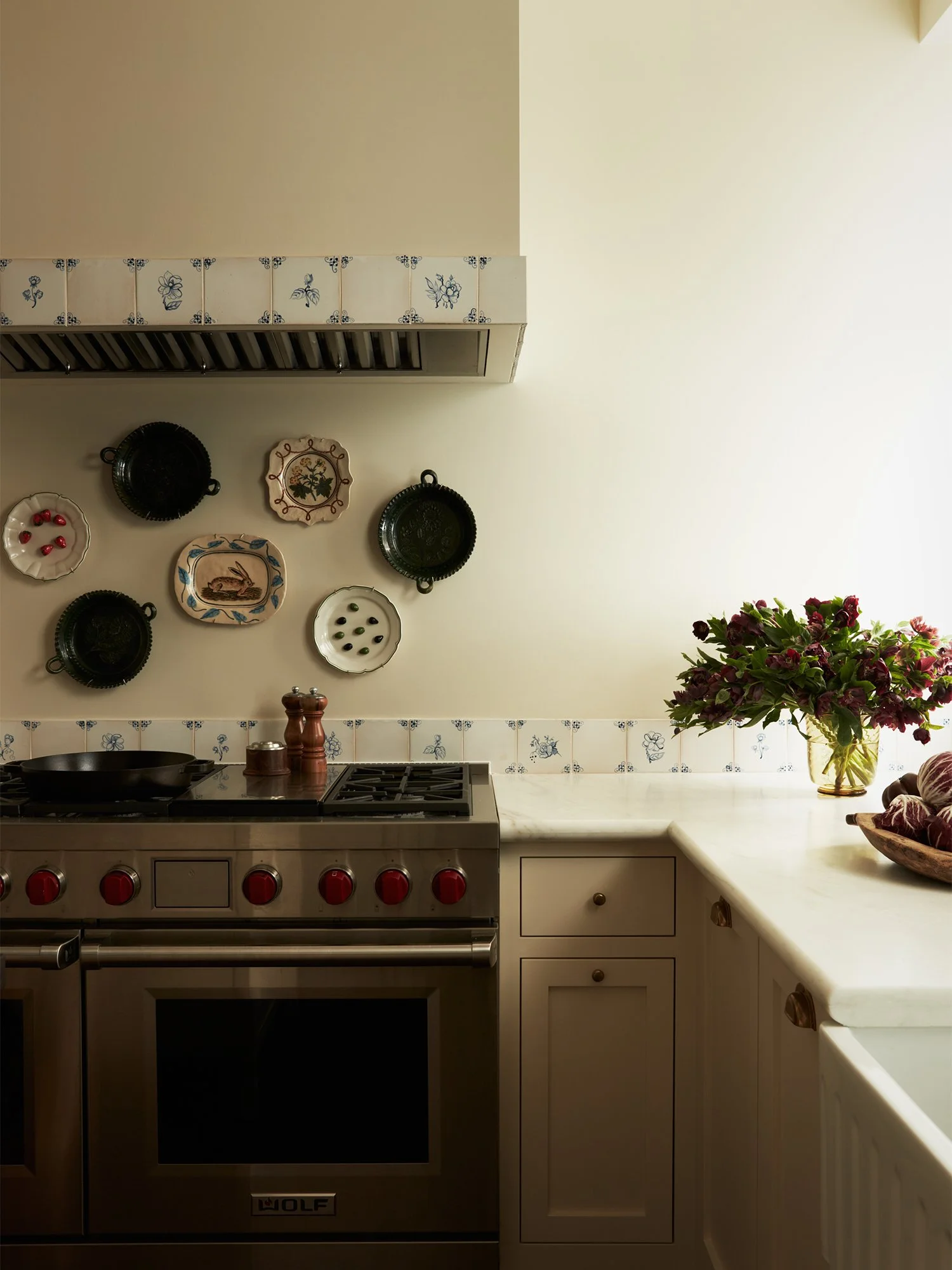 View of kitchen with stove and decorative plates on wall.
