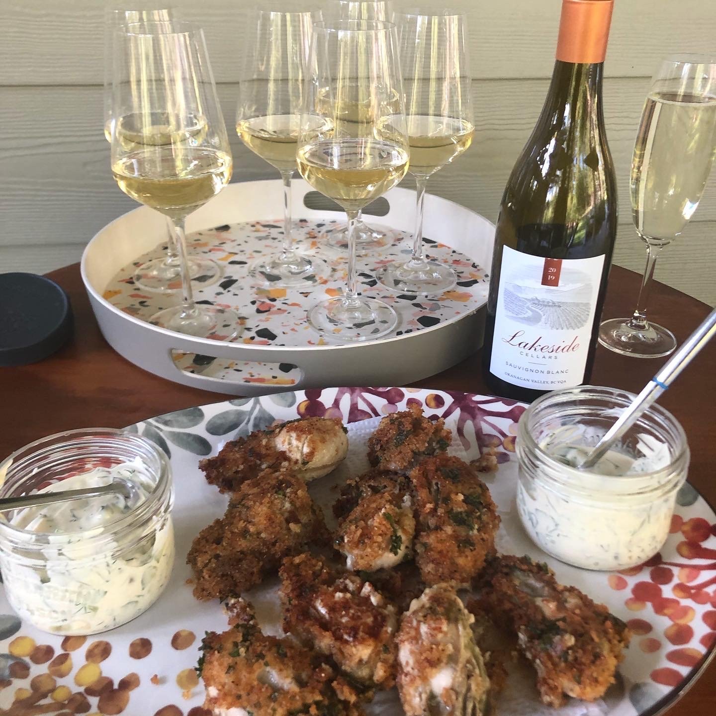 Beautifully styled table setting with white wine glasses, pan fried oysters for entertaining.