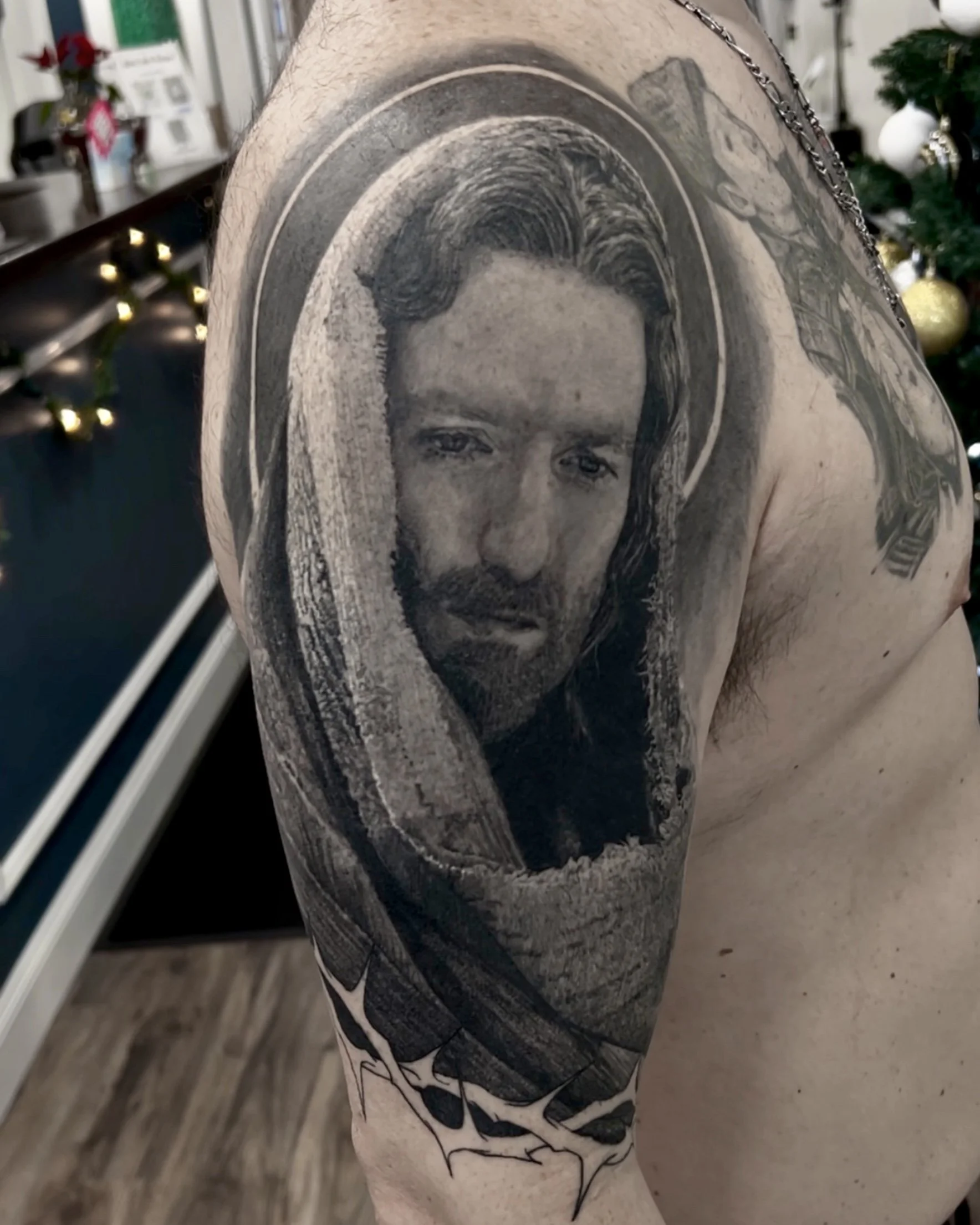 Healed hooded Jesus portrait realism tattoo on the shoulder by Etgar Oak