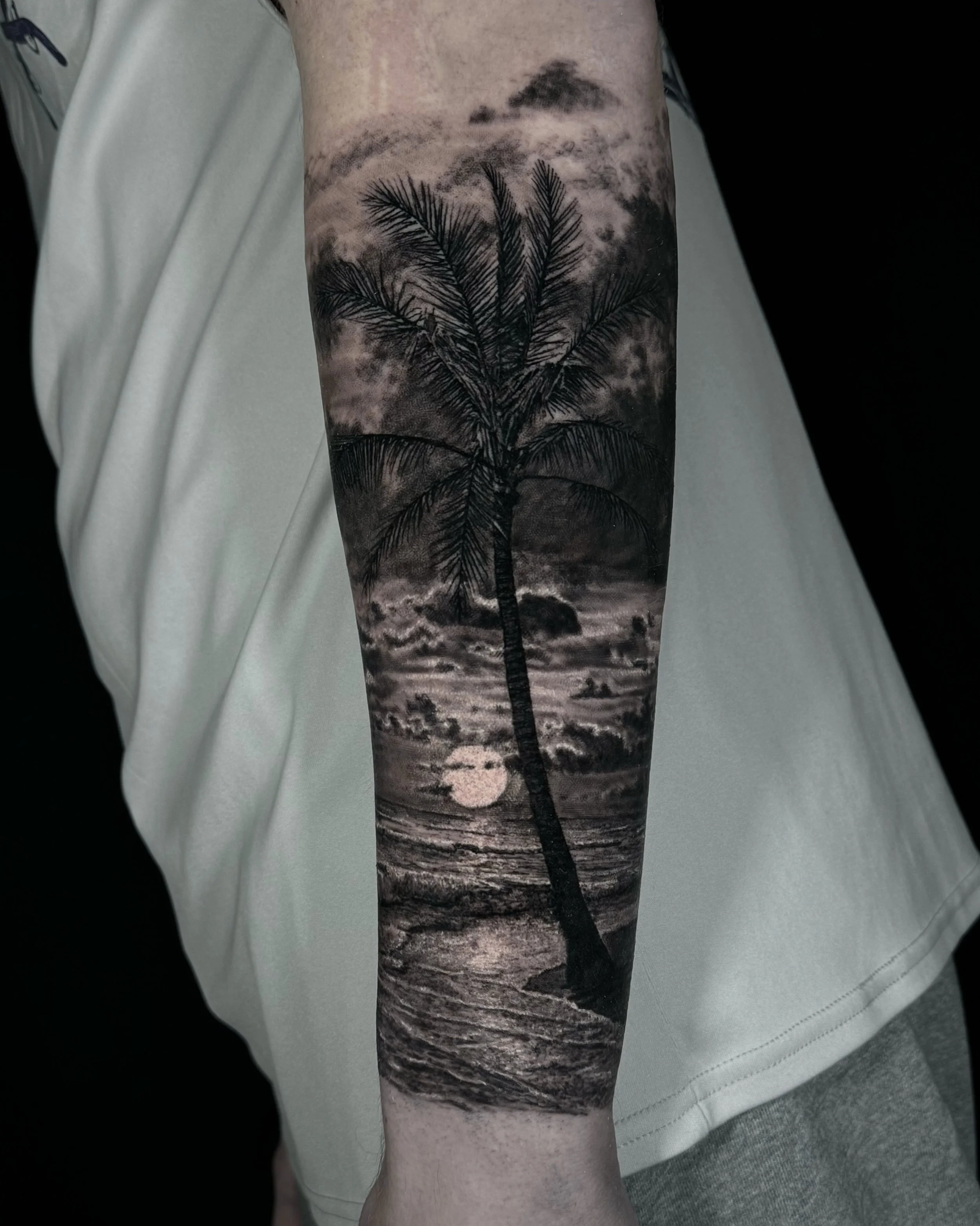 Palm tree and ocean sunset realism tattoo on the forearm by Etgar Oak