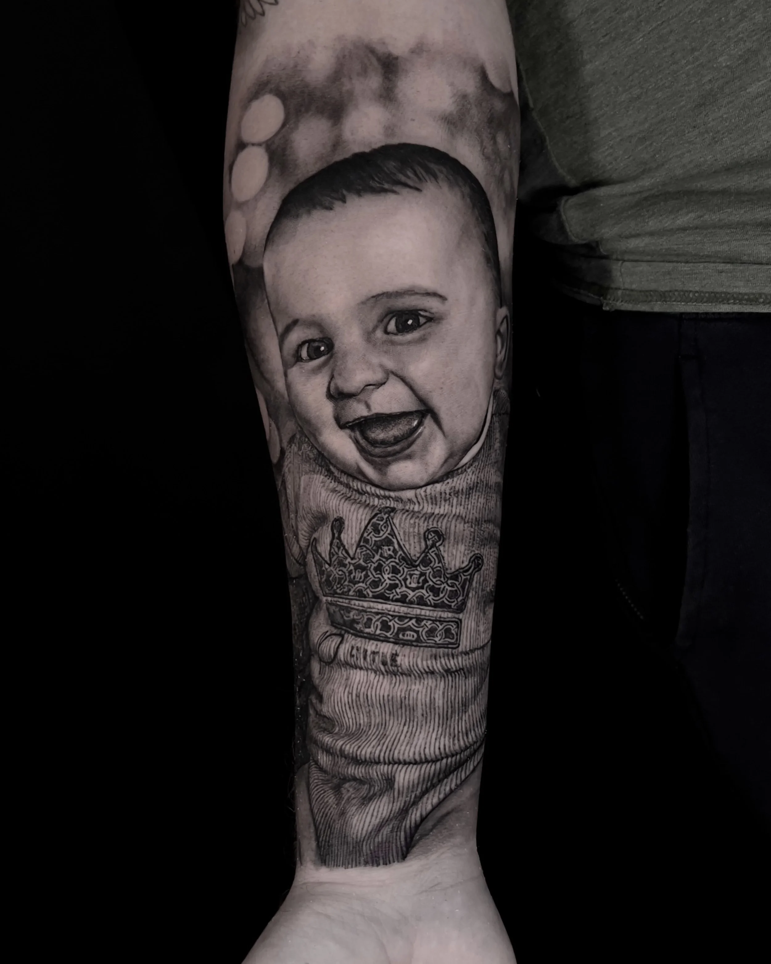 Baby portrait with crown realism tattoo on the forearm by Etgar Oak