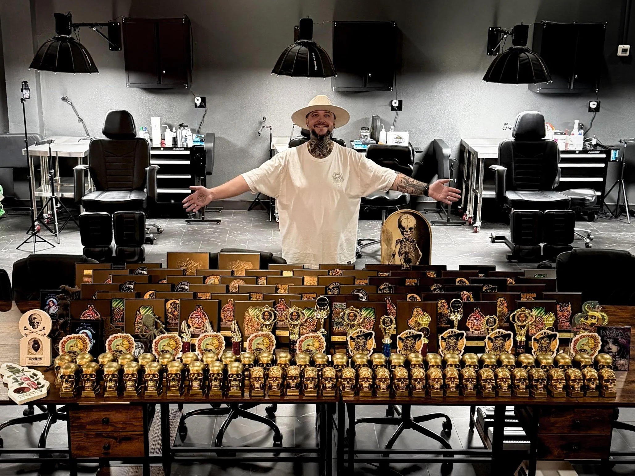 Etgar Oak standing in his studio behind tables covered with his tattoo awards