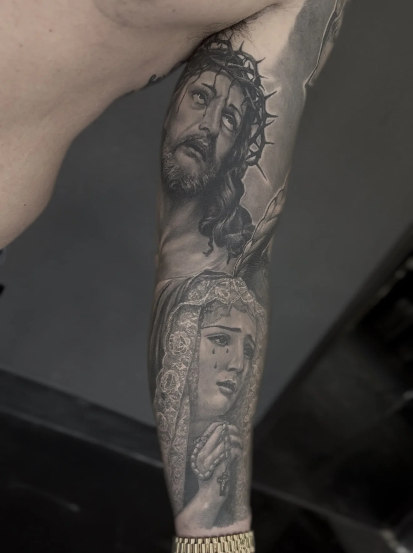 Healed Jesus with crown of thorns and praying Virgin Mary sleeve realism tattoo on the inner arm by Etgar Oak