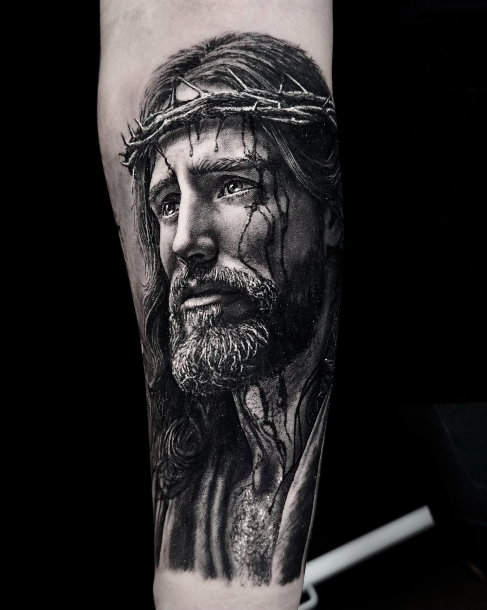 Jesus looking up with crown of thorns realism tattoo on the forearm by Etgar Oak
