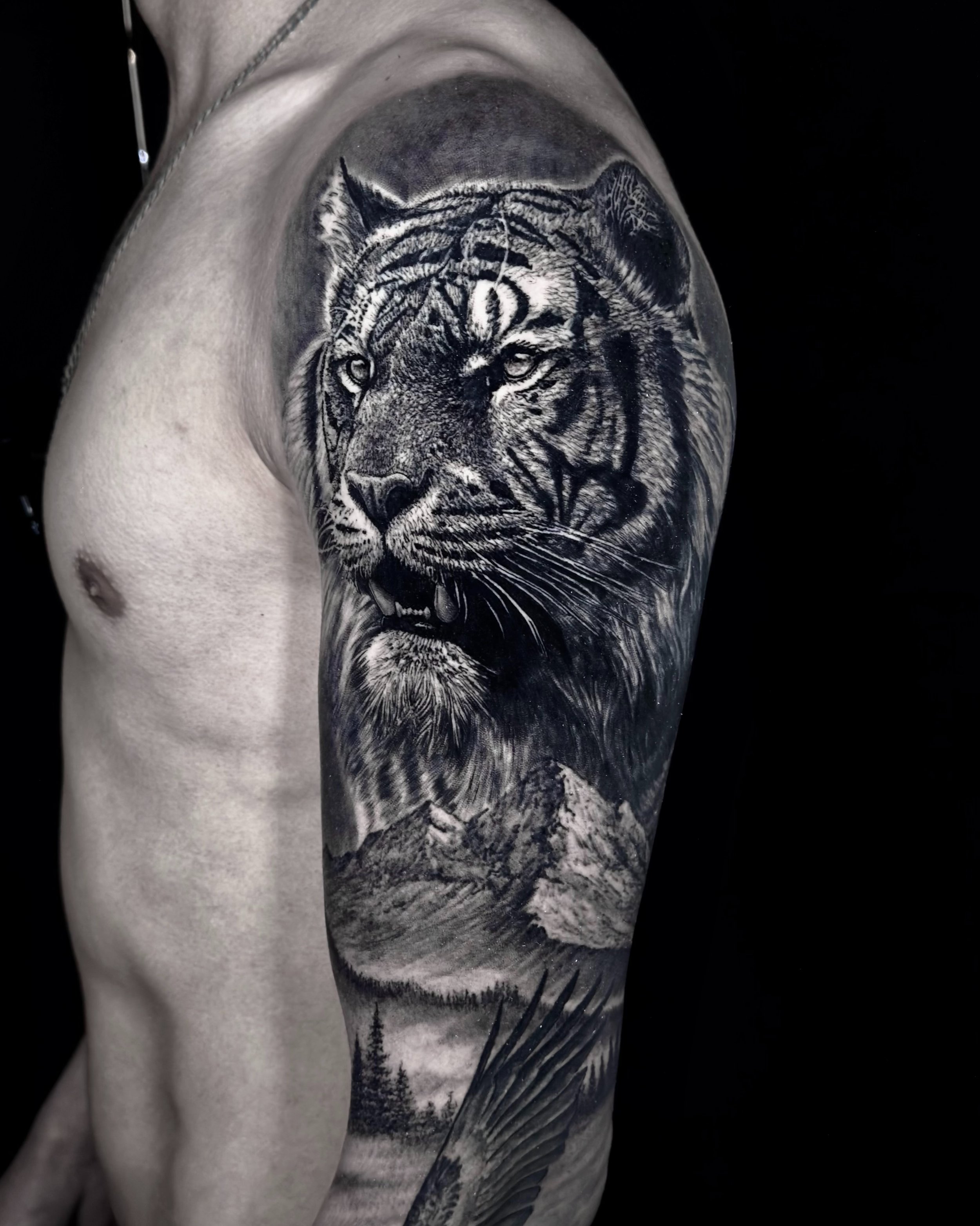 Tiger and mountains realism tattoo on the upper arm by Etgar Oak
