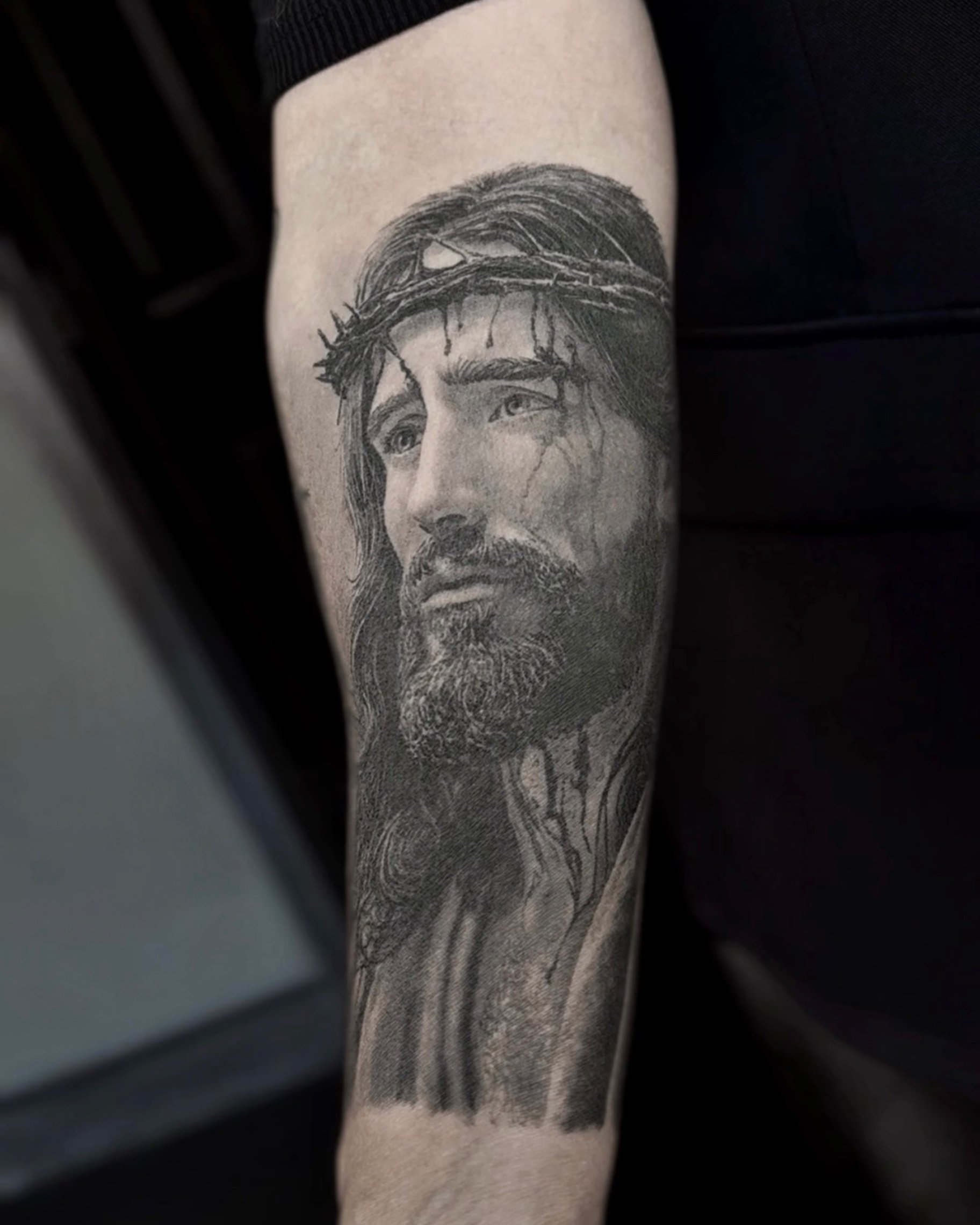 Healed Jesus looking up with crown of thorns realism tattoo on the forearm by Etgar Oak