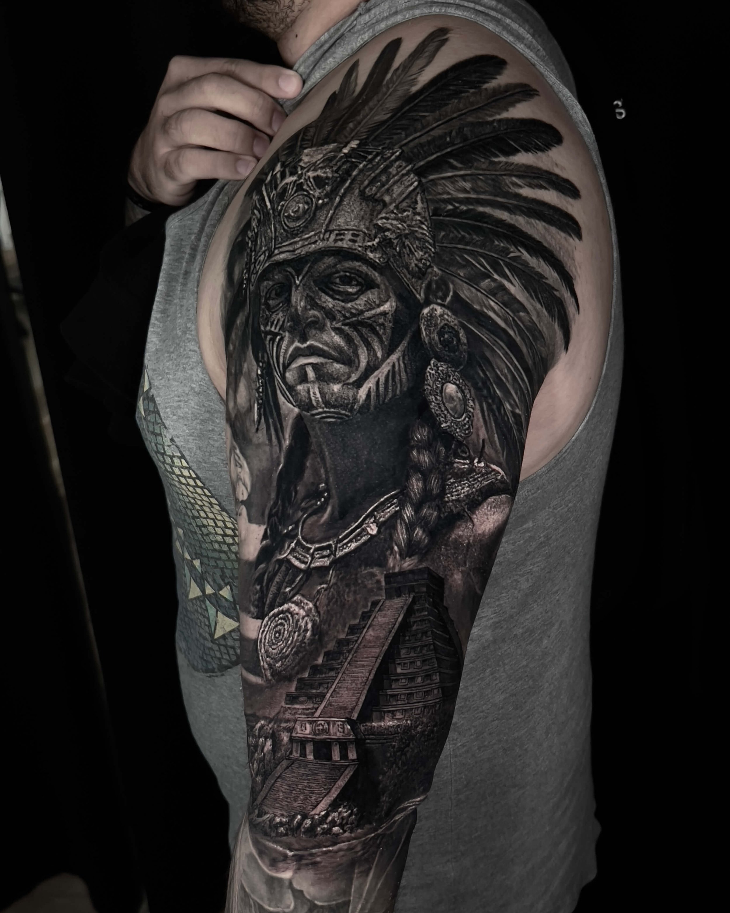 Native American chief in feathered headdress realism tattoo on the upper arm by Etgar Oak