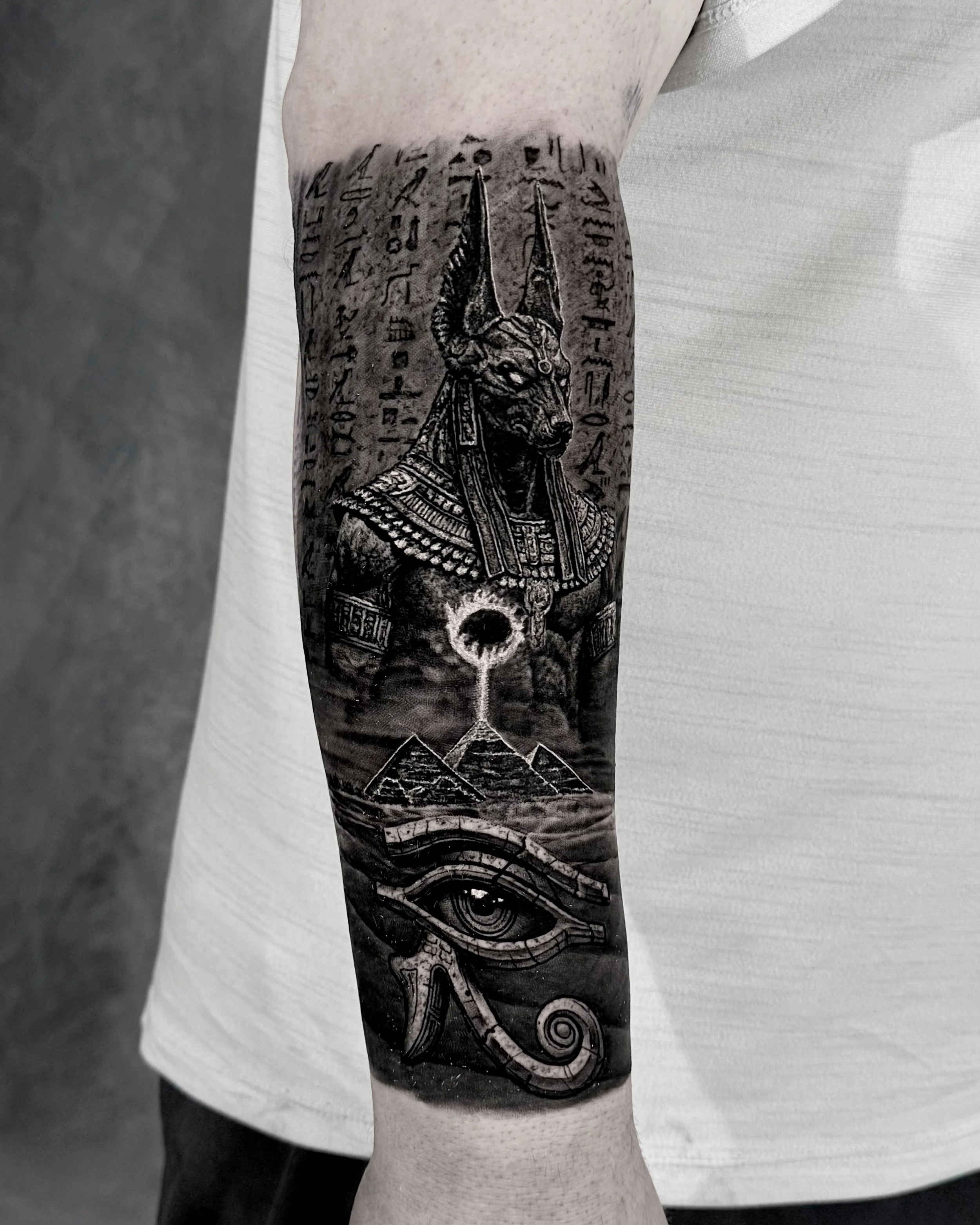 Anubis with pyramids and Eye of Horus realism tattoo on the forearm by Etgar Oak