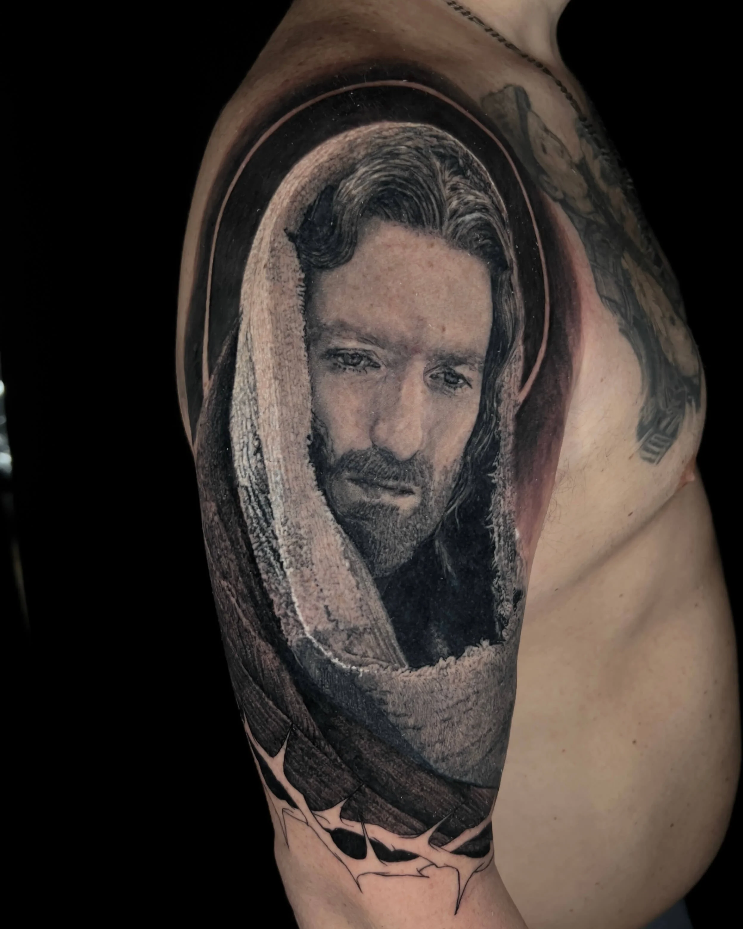 Hooded Jesus portrait realism tattoo on the shoulder by Etgar Oak