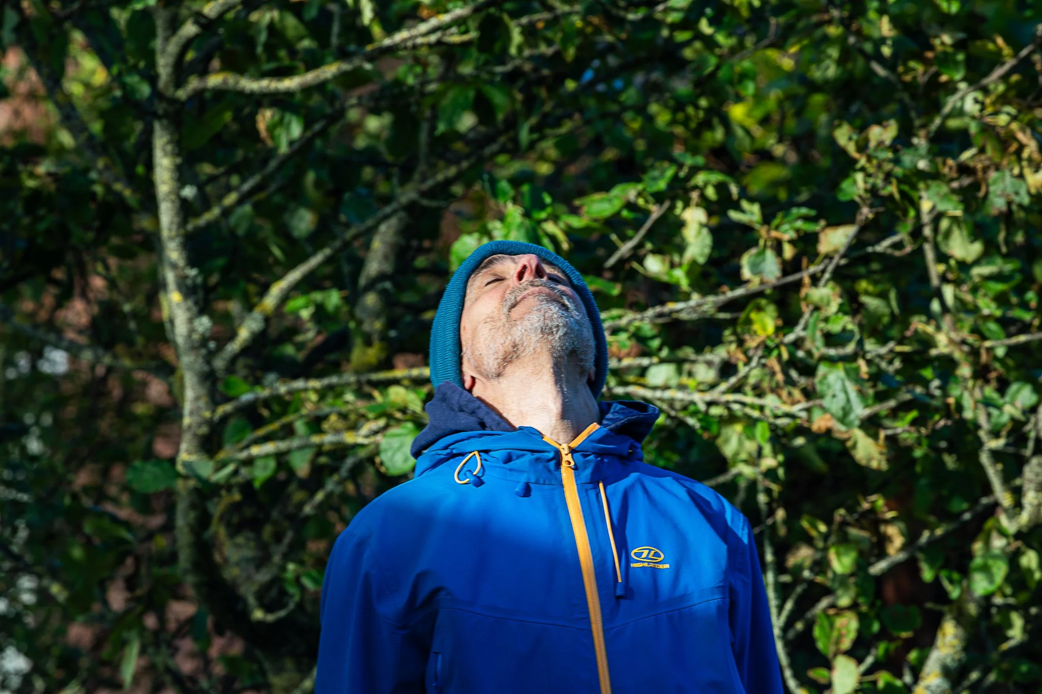 Man in a blue jacket doing mindful breathing in nature. Meditative breath work exercise during nature photography retreat in Scotland