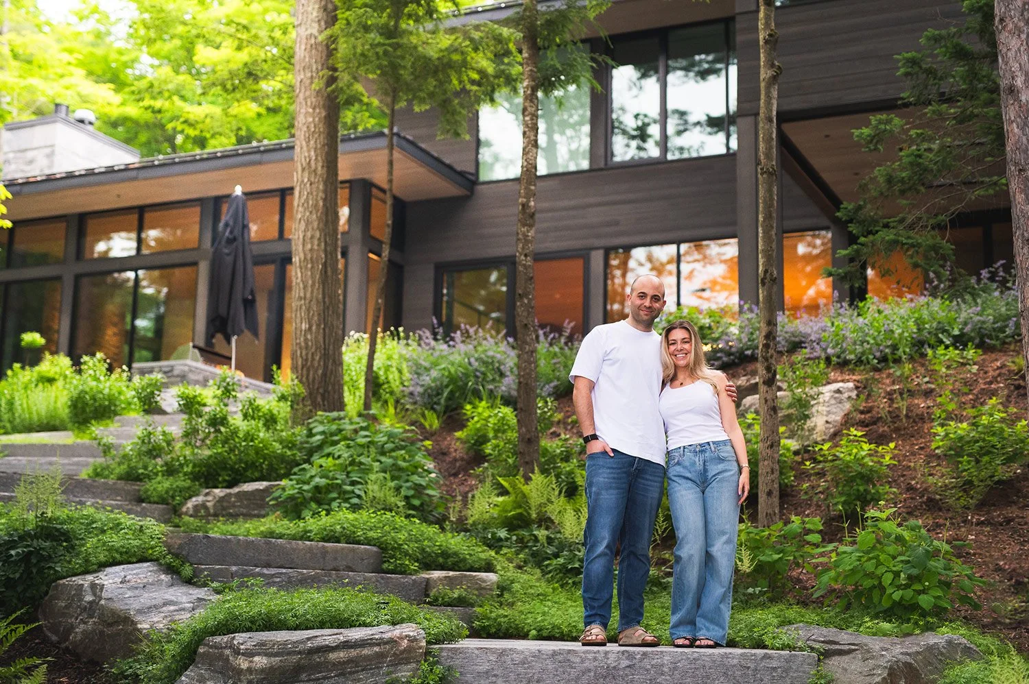 Engaged couple posing in front of their Muskoka cottage after their marriage proposal