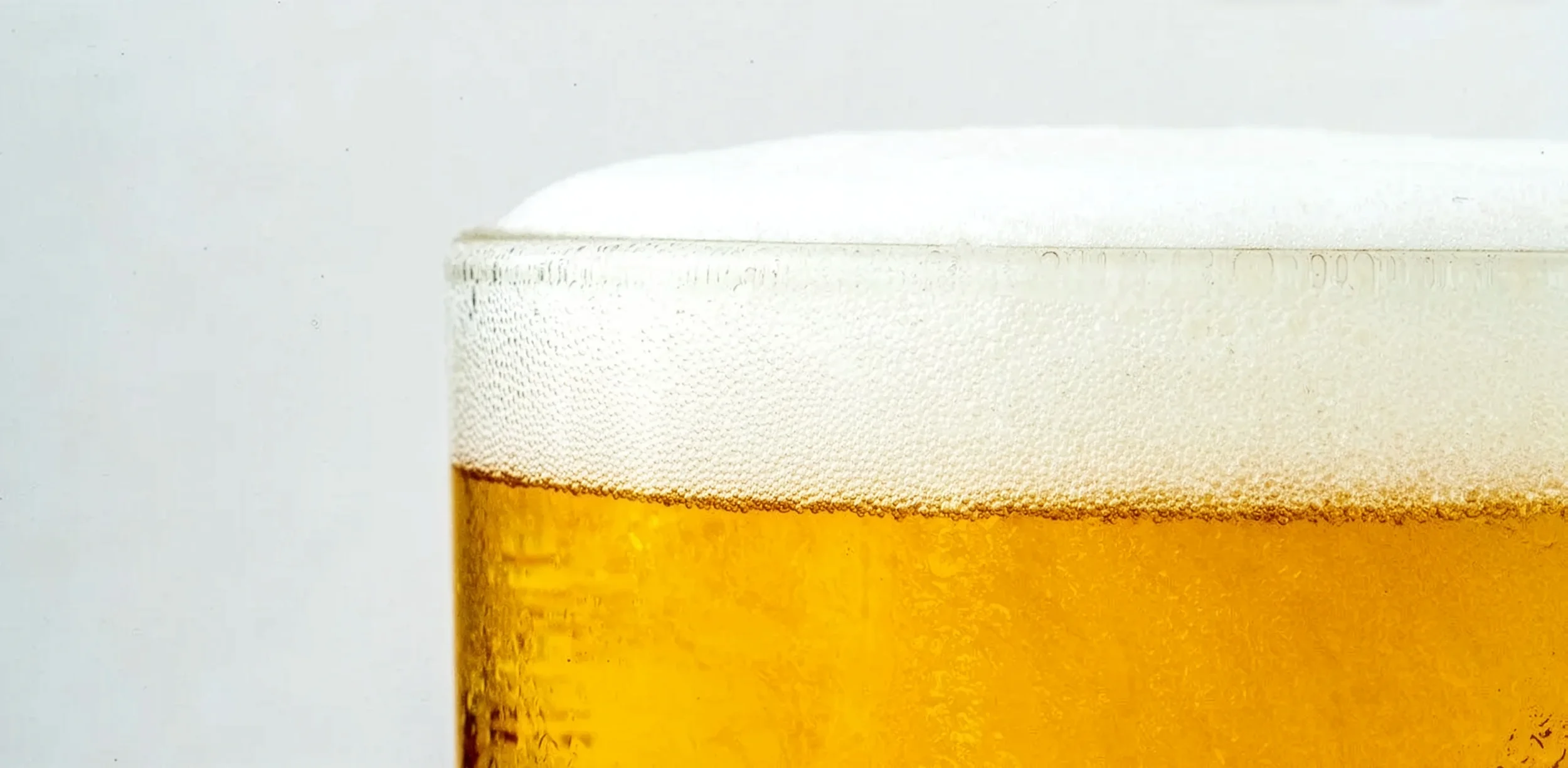 Close up image of a pint of beer showing excess foaming.