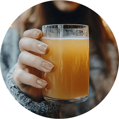 Person holding a glass of kombucha.