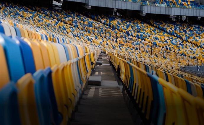Empty stadium seats in blue, yellow, and white colors with a view down the aisle