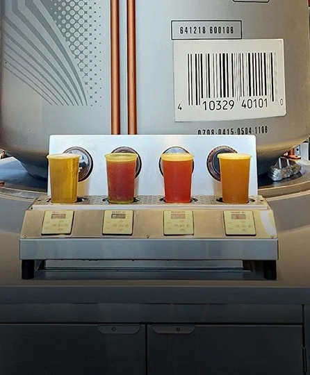 Four beer cups arranged in a row on top of ReverseTap beer dispenser.