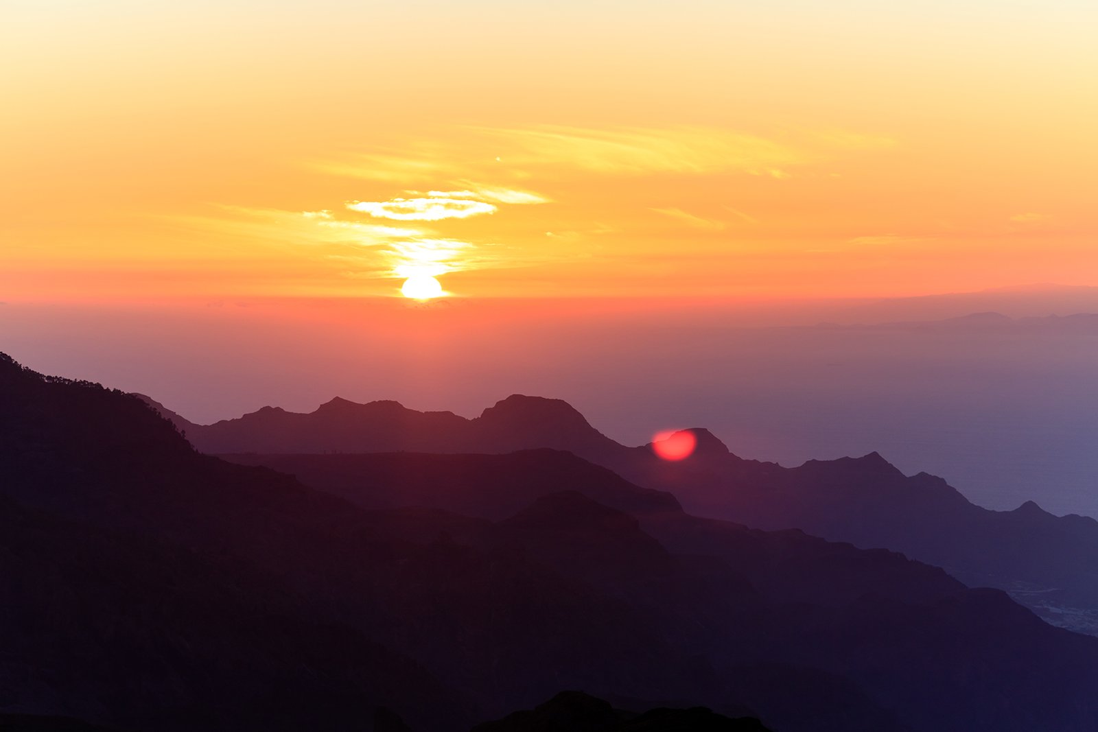 Sunset over mountain ranges with colorful sky and clouds.