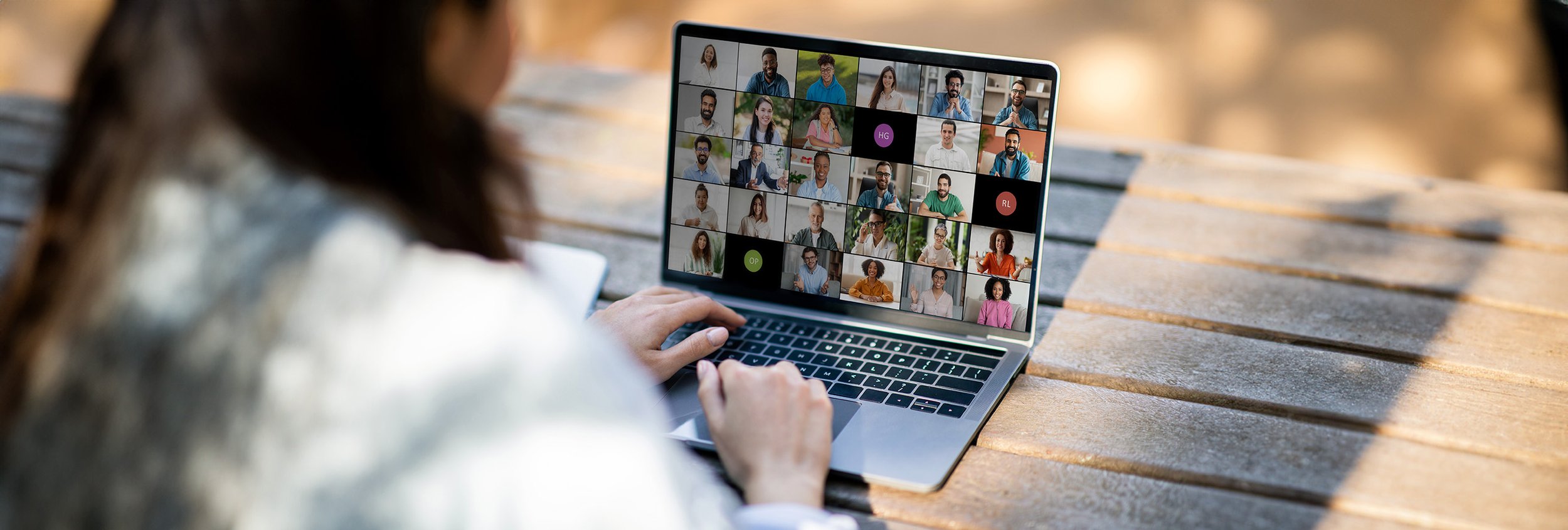 Person participating in a virtual video conference call on a laptop, with multiple people displayed in individual video tiles.