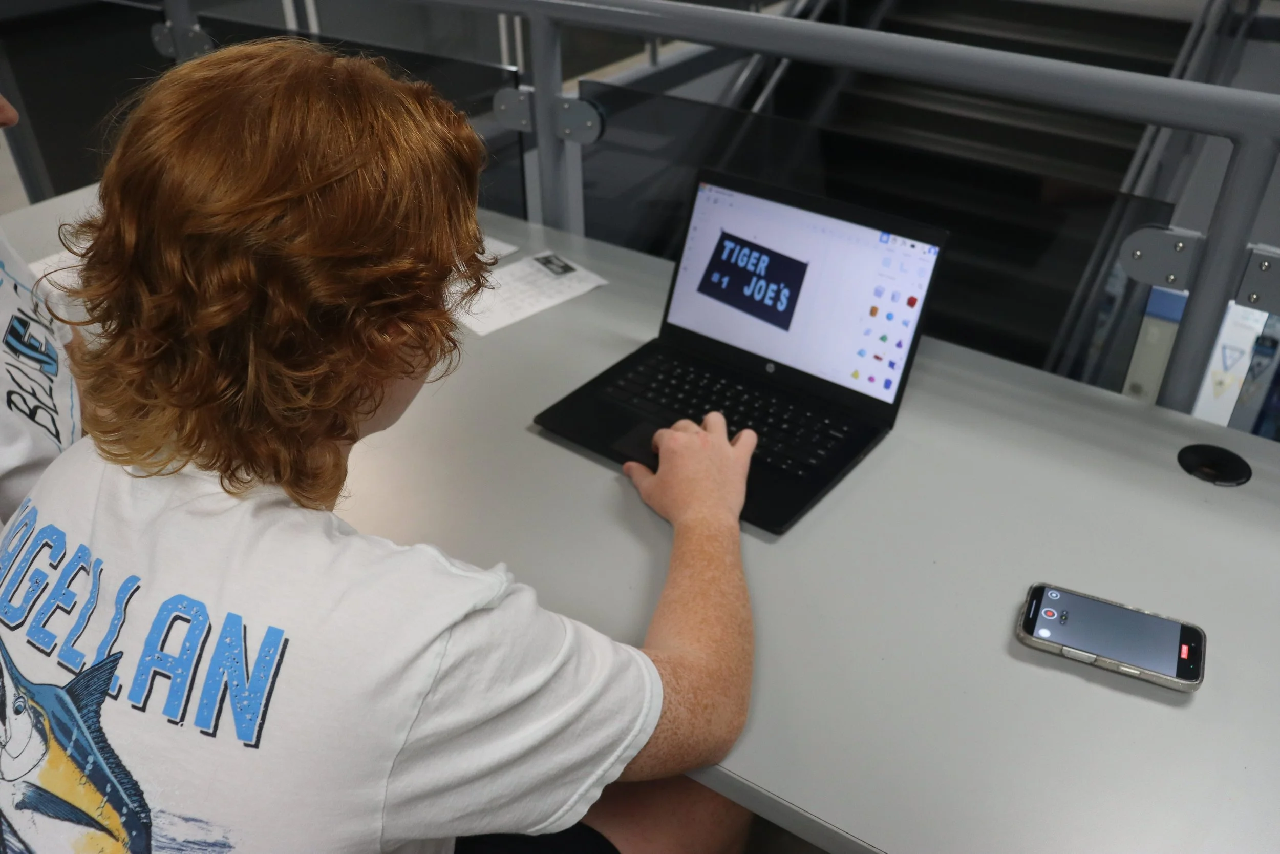 Freshman Ethan Viola works on his sign for Tiger Joe’s coffee cart. Rachel McCormick’s engineering class put their new 3D printers to good use making the designs for the cup and lid holders for the cart. Tiger Joe’s teacher, Kris Spradley, vo