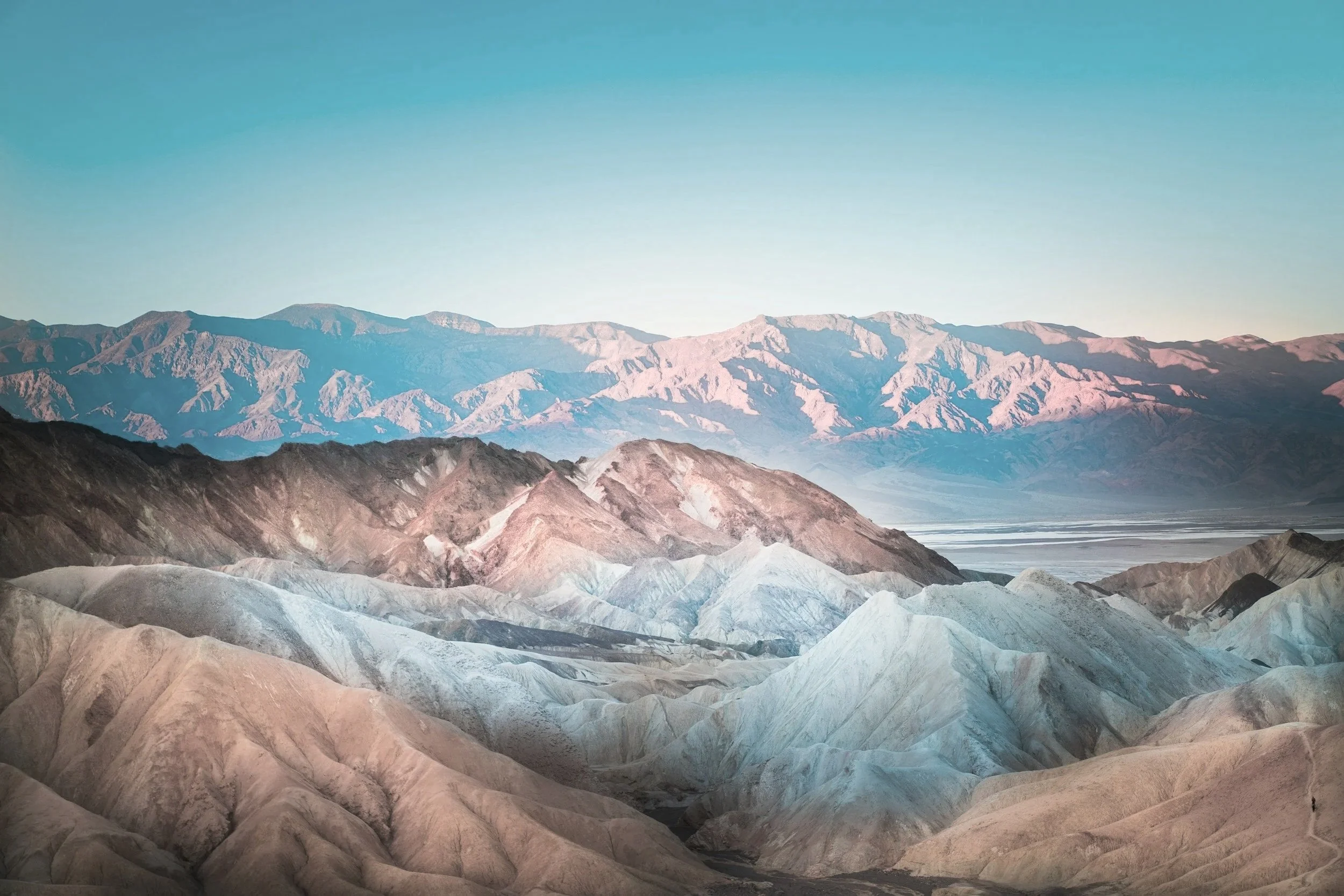 Scenic view of colorful mountain landscape with layered hills and distant mountains under a clear sky.